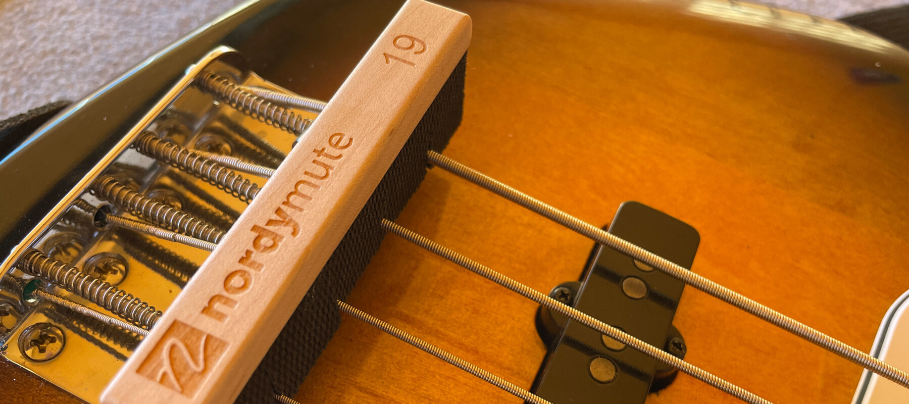 A Nordstrand NordyMute mounted on the strings in front of a vintage bridge