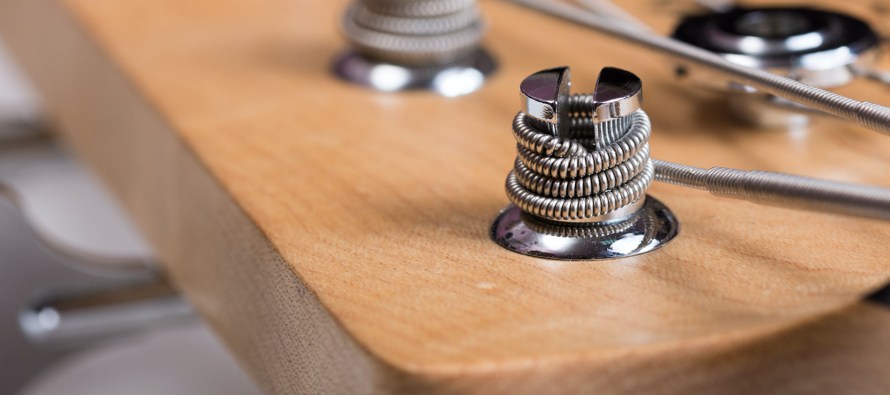 Photo of a Tuner Post holding strings on a bass headstock