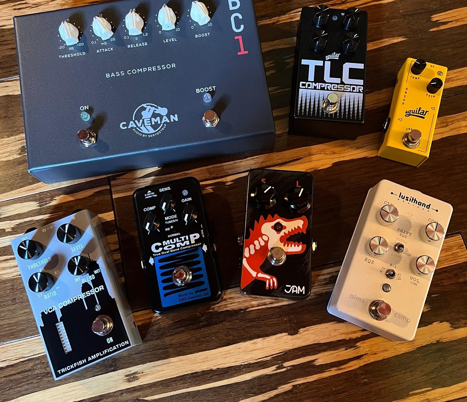 Bass Compression Pedals on hardwood floor, featuring Caveman, Aguilar, Trickfish, EBS, JAM and Lusithand pedals